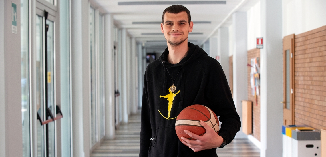 Marko Krstanovic steht in einem Gang – mit dem Basketball in der Hand und einer Don Bosco-Kette um den Hals.