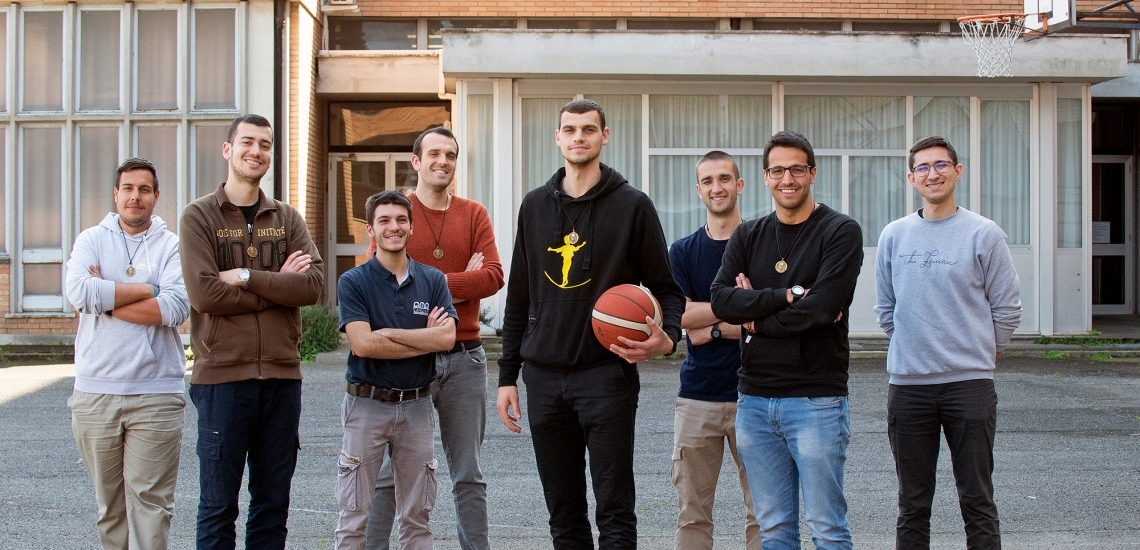 Marko Krstanović und sieben salesianische Mitbrüder stehen auf einem Sportplatz. Er ist in der Mitte mit einem Basketball.