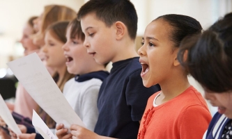 Schülerinnen und Schülern stehen im Schulchor in einer Reihe und singen nach Noten