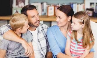 Eltern und Kinder sitzen eng zusammen und sprechen angeregt miteinander