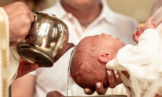 Priester gießt Baby bei Taufe Wasser über den Kopf