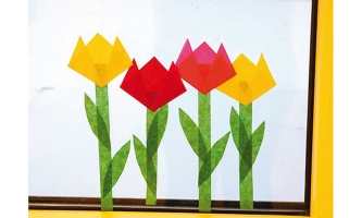 Vier selbst gemachte Tulpen aus Transparentpapier am Fenster 