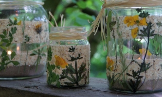 drei mit Sand gefüllte Gläser mit Blumen und Kerzen